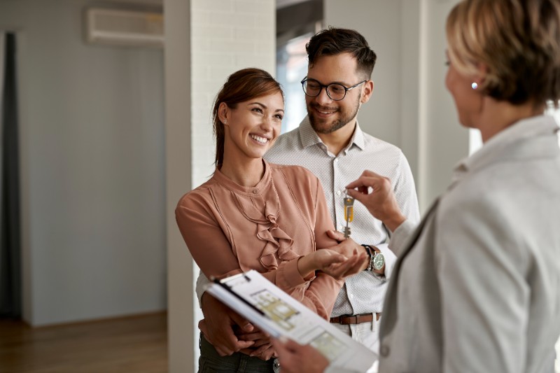 Young happy couple receiving keys of their new home from real estate agent